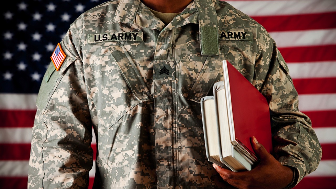 Soldier holding books in front of American Flag
