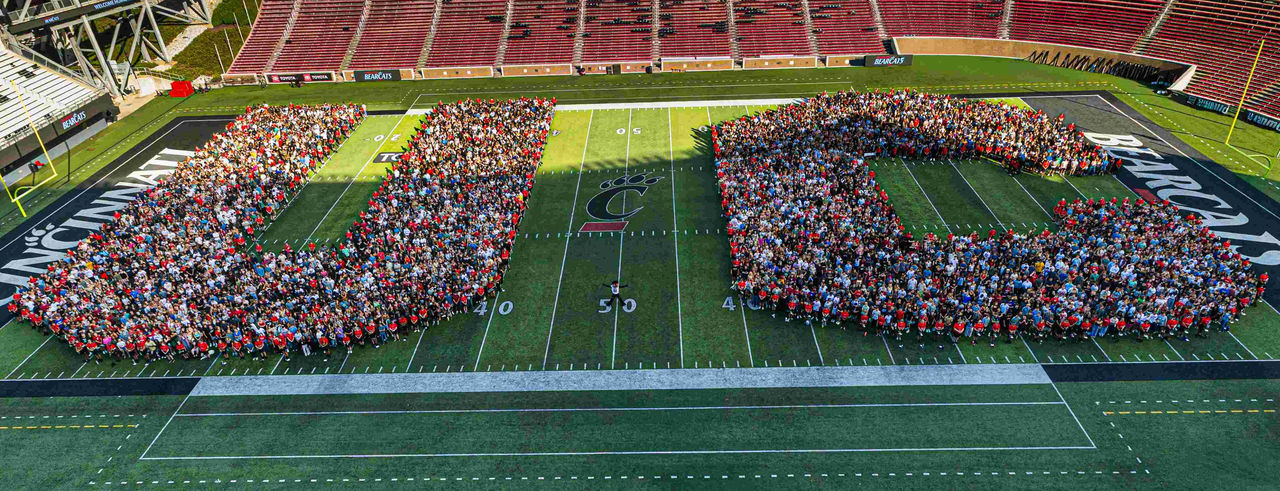 freshman from the fall of 2026 class stand together in the shape of the letters "UC" on nippert stadium during welcome week. 