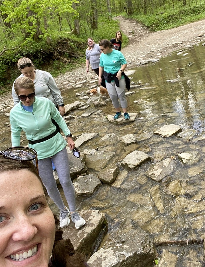 Women hiking in the woods across a stream
