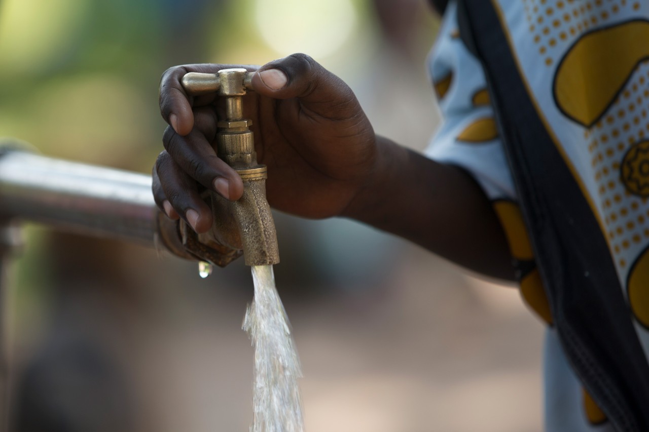 A hand shown turning a running faucet in Tanzania