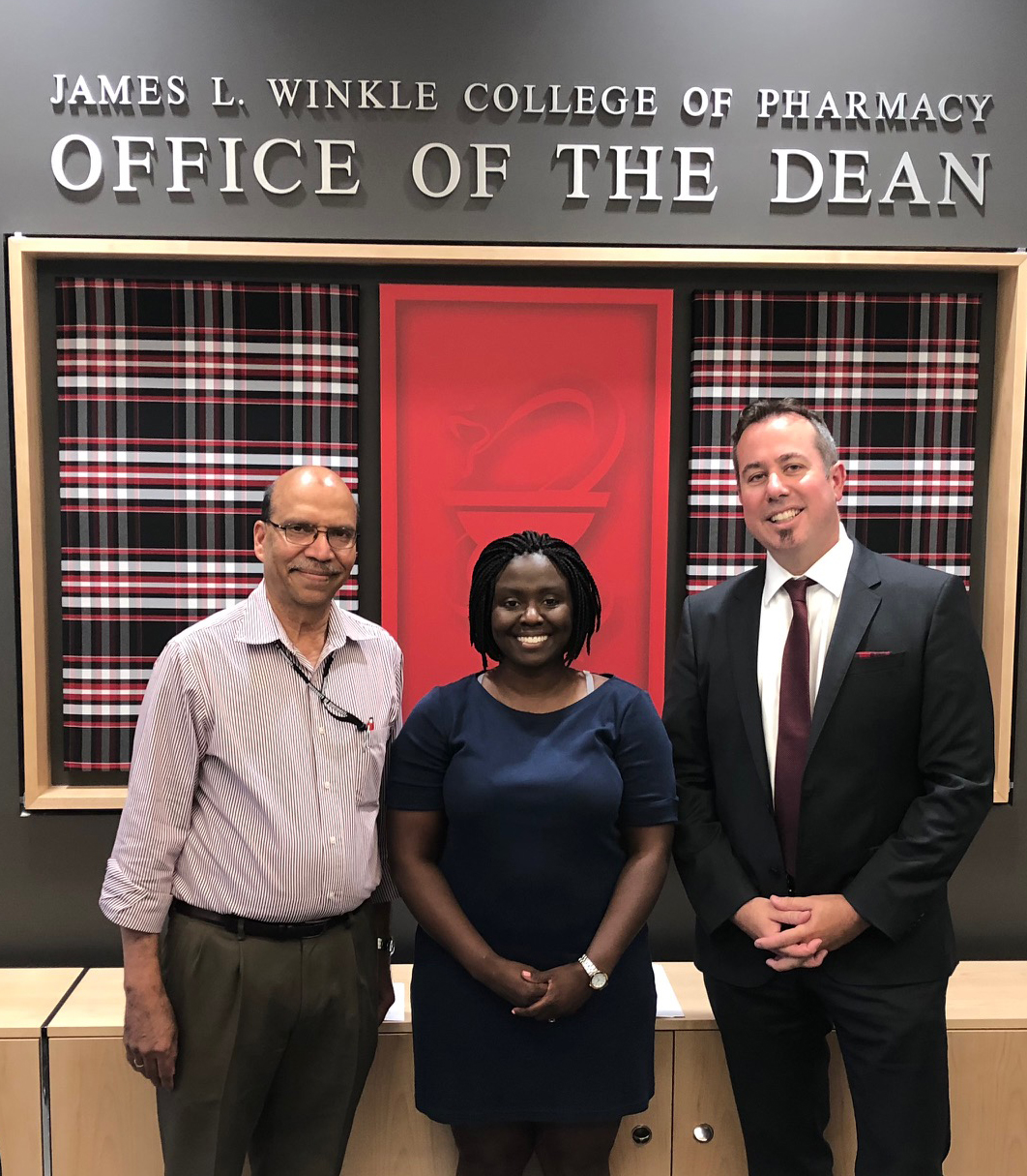 Graduation photo of Eunice Cofie-Obeng with Dean MacKinnon and Dr. Anath in the dean's suite.