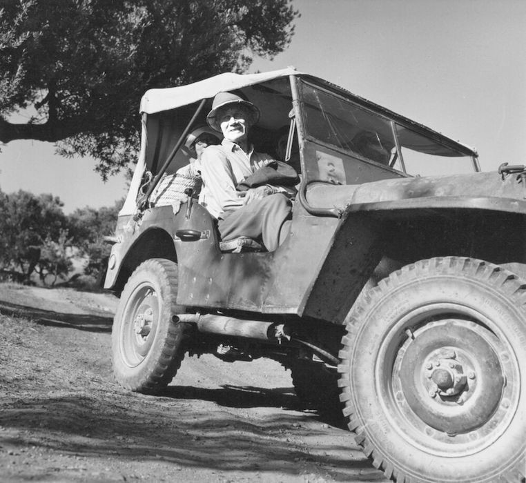 Black and white photo of a man in a Jeep rover