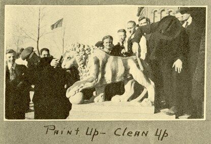 Students painting a lion statue