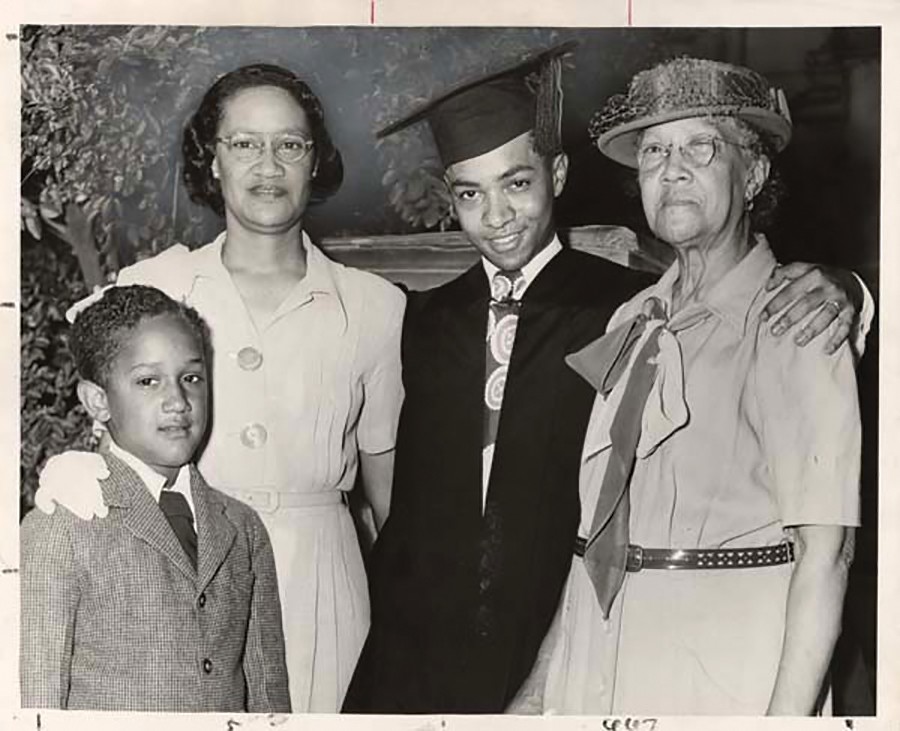 Black and white photo of a graduate in cap and gown, his mother, grandmother and little brother