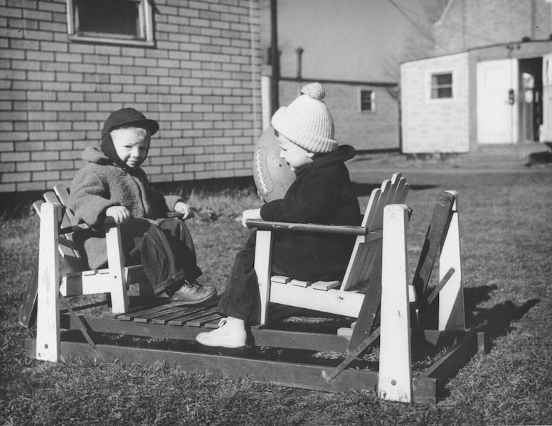 Black and white photo of two young children playing with a football