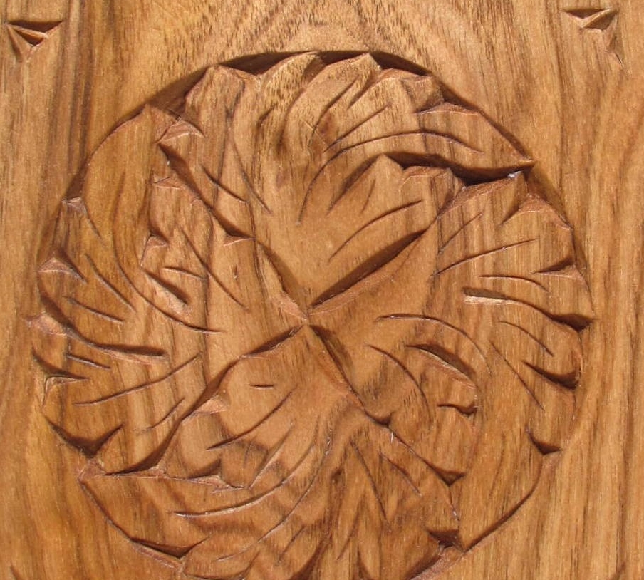 square piece of wood with decorative carvings