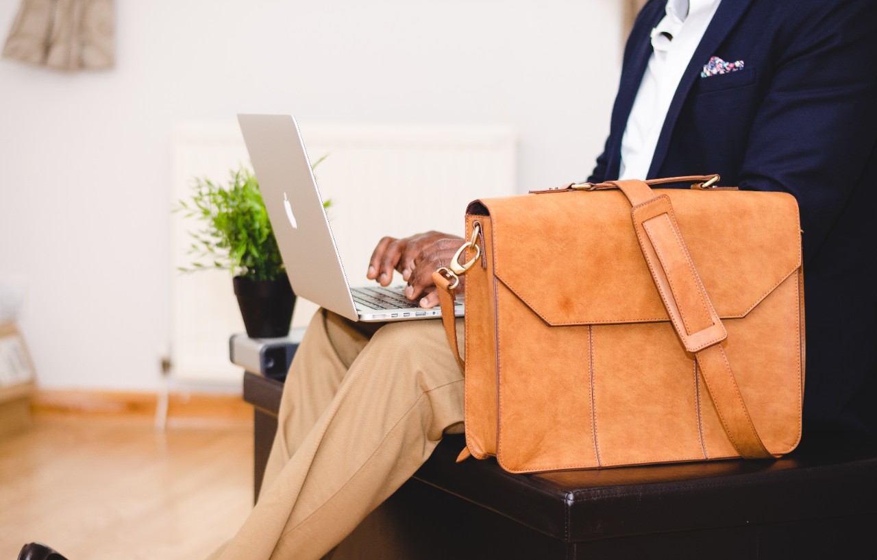 man wearing a business suit with briefcase using laptop