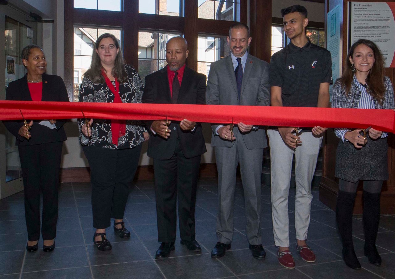 University leaders stand behind a giant red ribbon