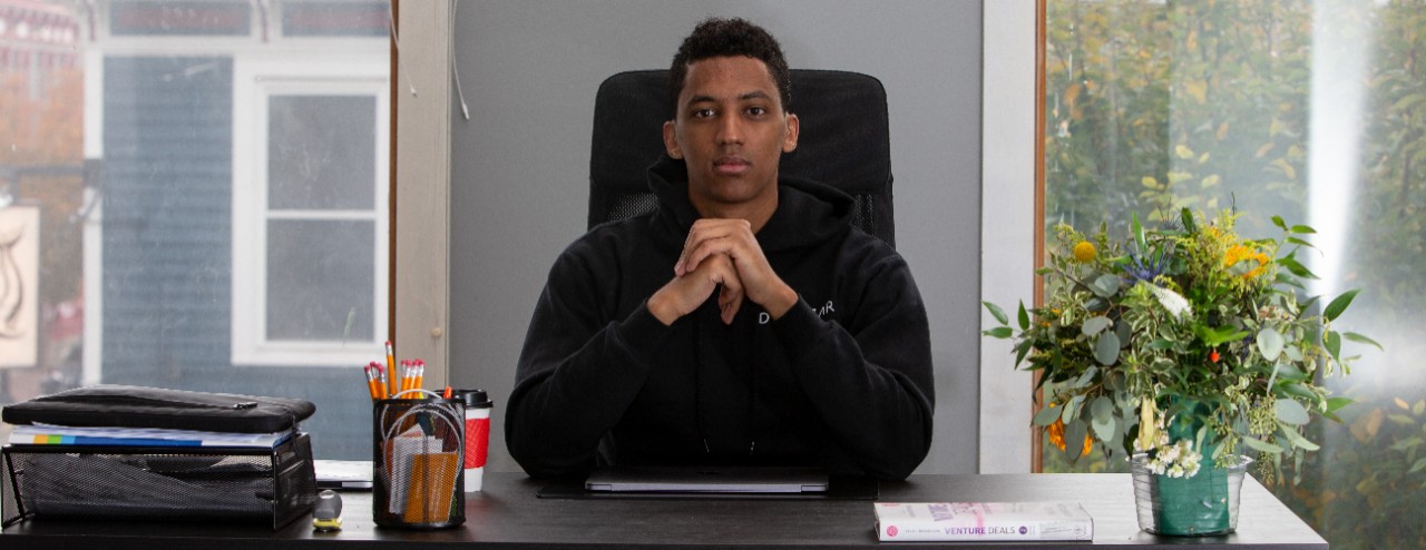 Aman Tsegai sits at his office desk with his hands folded in front of him.