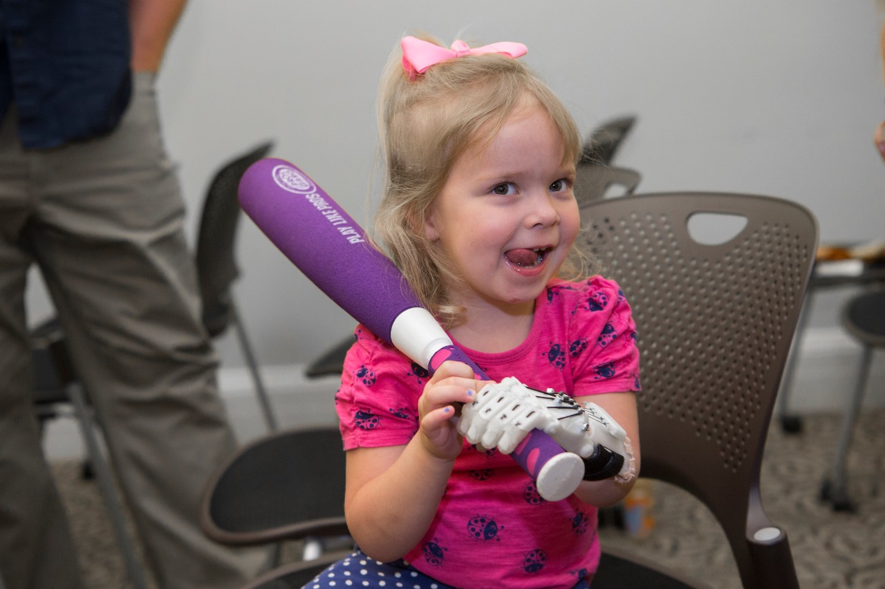 Ella Morton, right of Dayton Ohio age 3 year old used her 3-D prosthetic hand made by UC students to shake hands with University of Cincinnati president Neville G. Pinto during UC Board Meeting. UC/Joseph Fuqua II