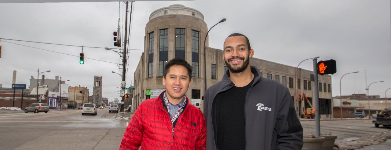 Marvin Abrinica and Brian Jackson wearing hardhats stand on a street corner outside the Paramount Building, which will soon be home to their new brewery.