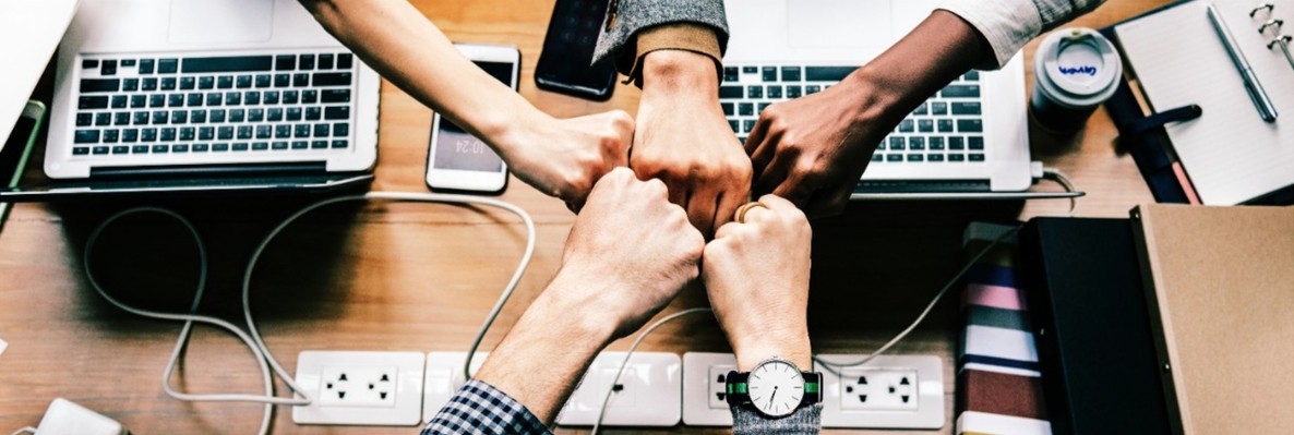 The new IT@UC get help banner; hands fist-bumping surrounded by technology