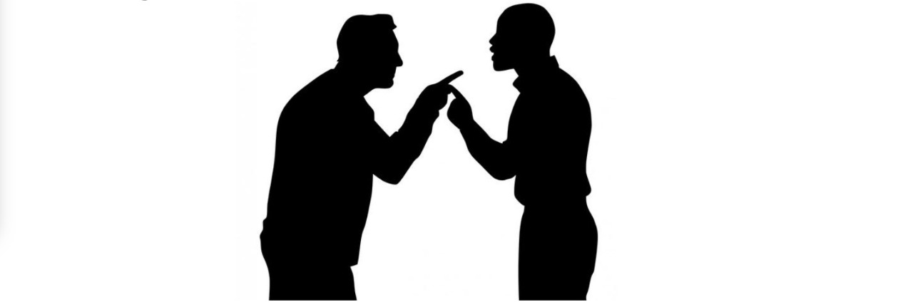 Two men in black silhouette against a white background point at each other