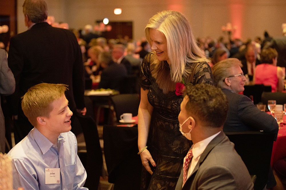 Lori Beer, standing, speaks with Julian Litvak and Mohamed Emlemdi, seated