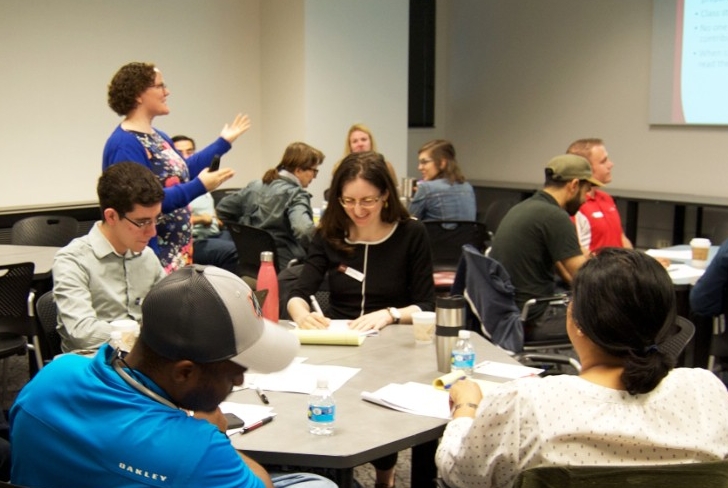 Students sit around a table in a workshop.