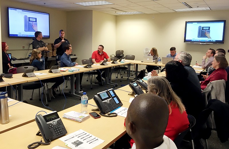 Session participants listen while presenters talk about new phones