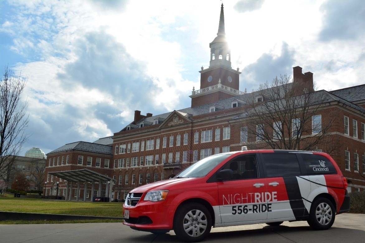 Red and white UC Night Ride van in front of McMicken Hall.