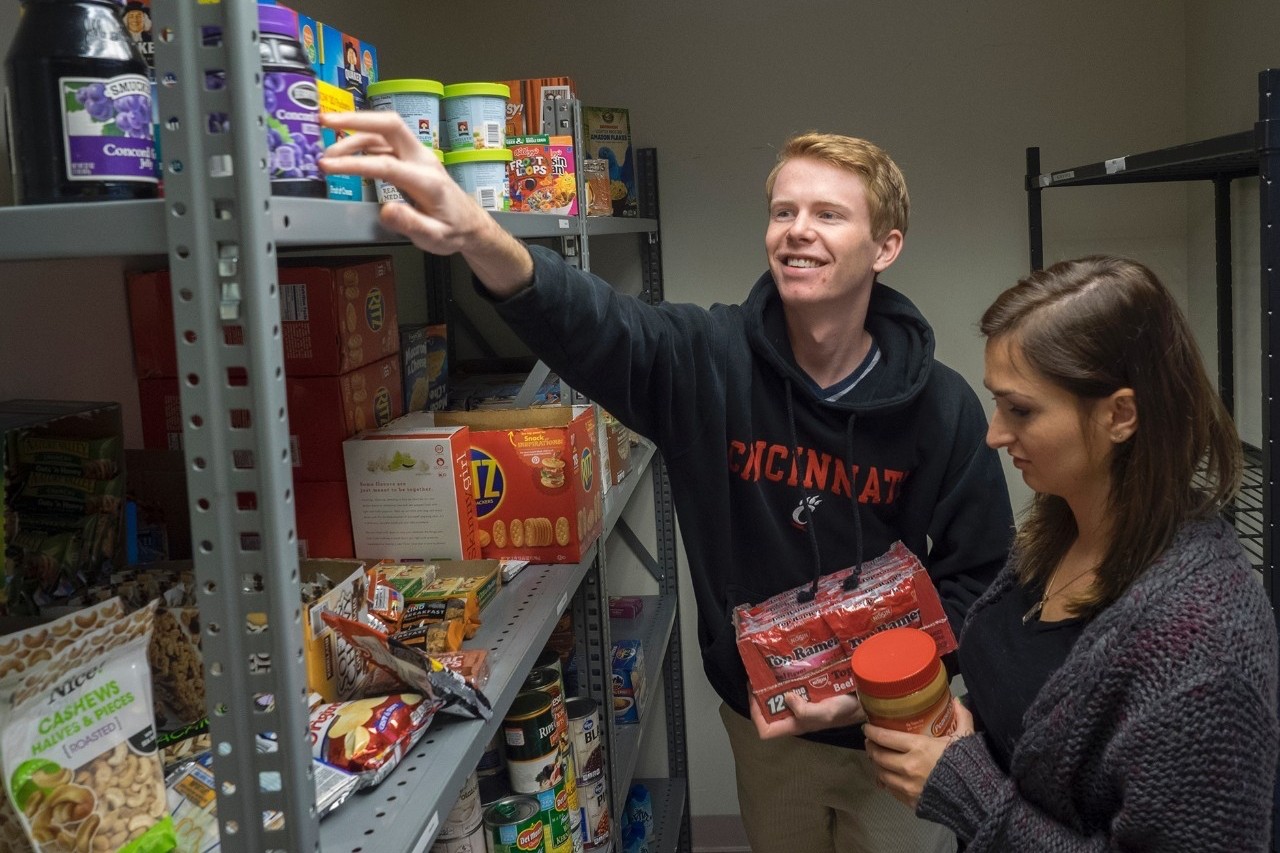 Two students reach fro food from a shelf.