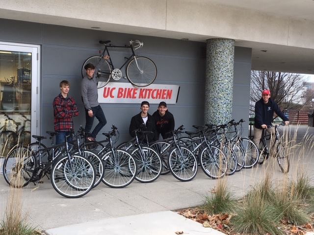 Several bicycles are lined up against a building at UC's Bike Kitchen.