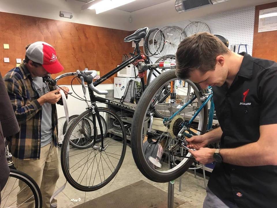 Two men work on a bicycle in a bike shop.