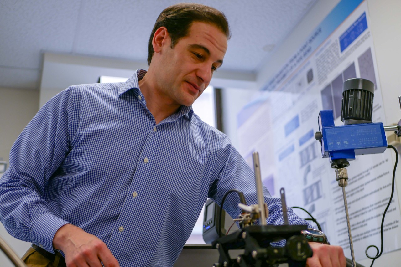Simonetti stands over a piece of equipment in his lab.