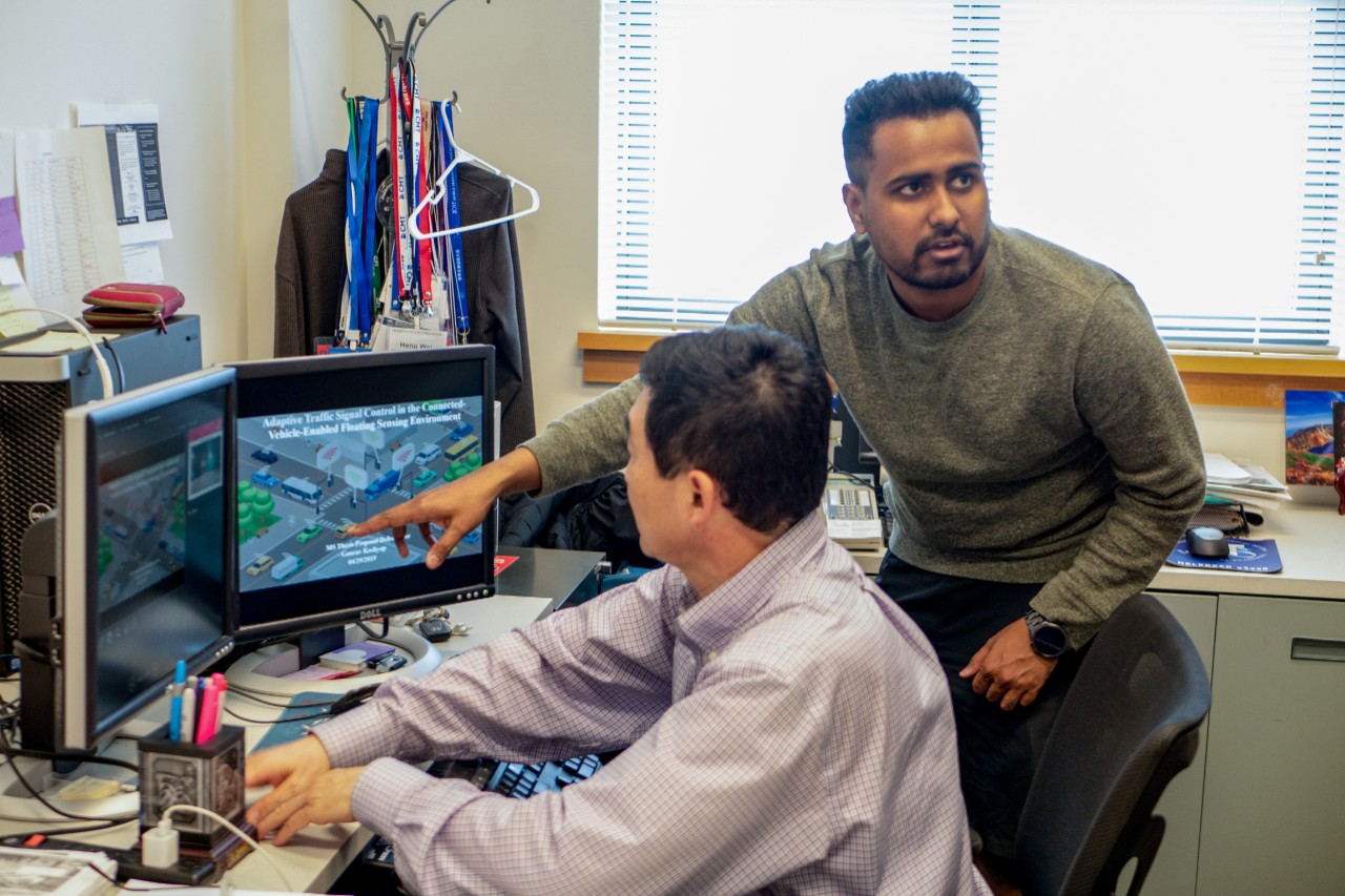 Kashyap and Wei talking about work in front of computer