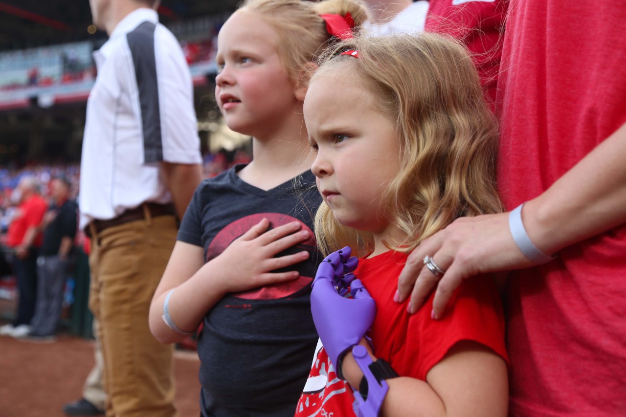 Ella Morton and her sister put their hands over their hearts during the playing of the National Anthem.