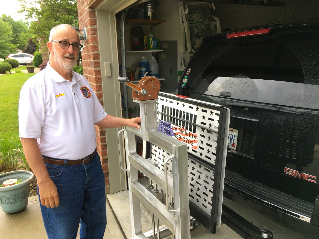 Mike Donnelly stands in his garage next to a lift holding his scooter rack.