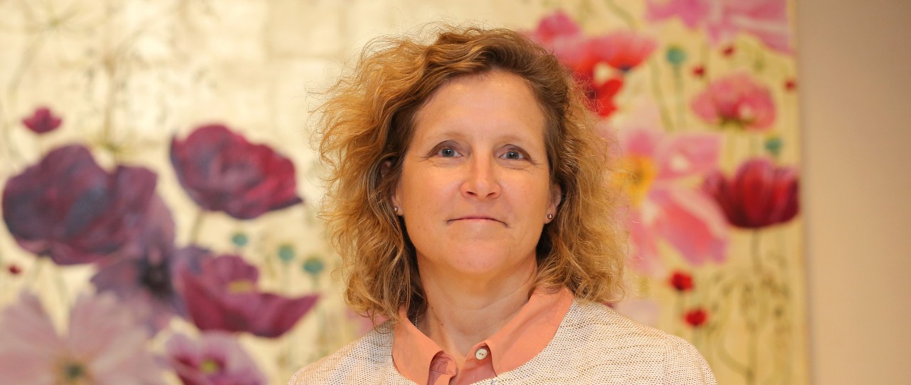 A woman standing in front of a picture of flowers
