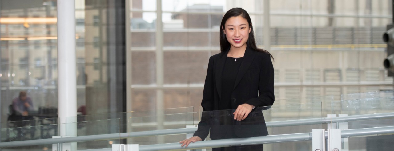 Dermatology resident Yang Yu, MD, standing on a bridge in the CARE/Crawley Building on the UC medical campus