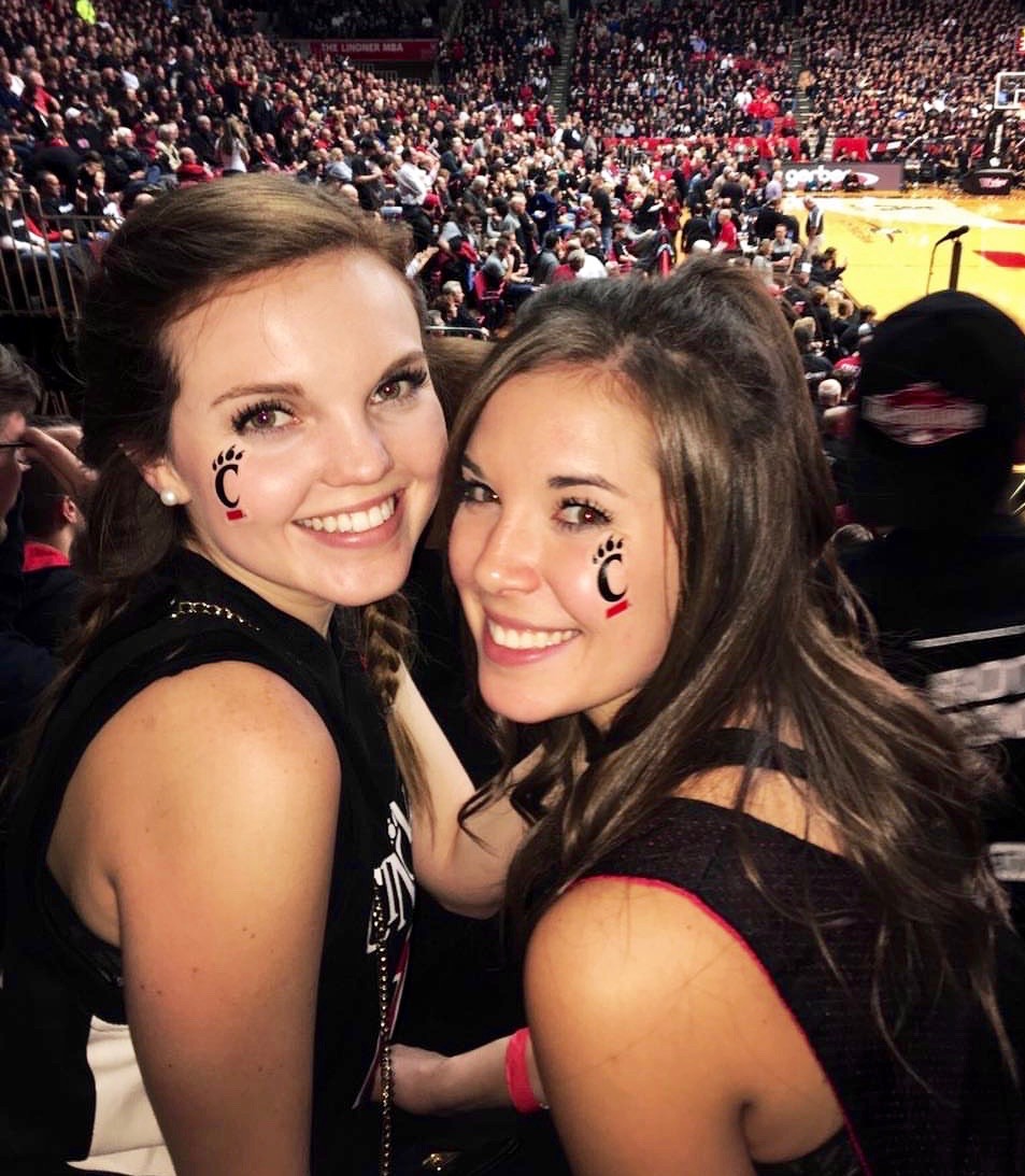 Amanda Bright, UC CECH student, poses with a woman at a UC basketball game.
