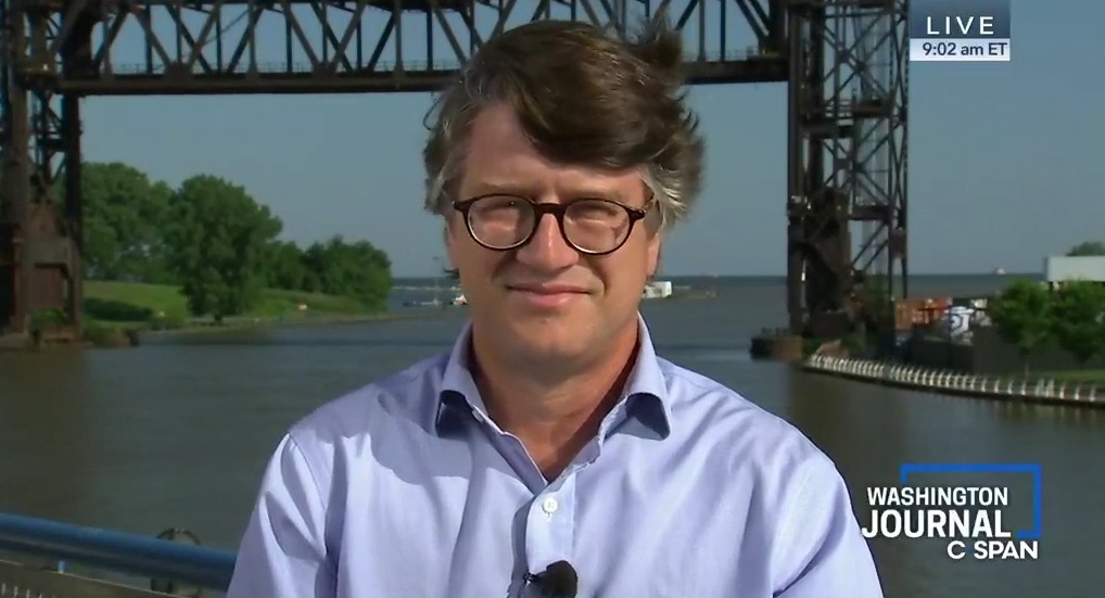 man standing in front of river and bridge