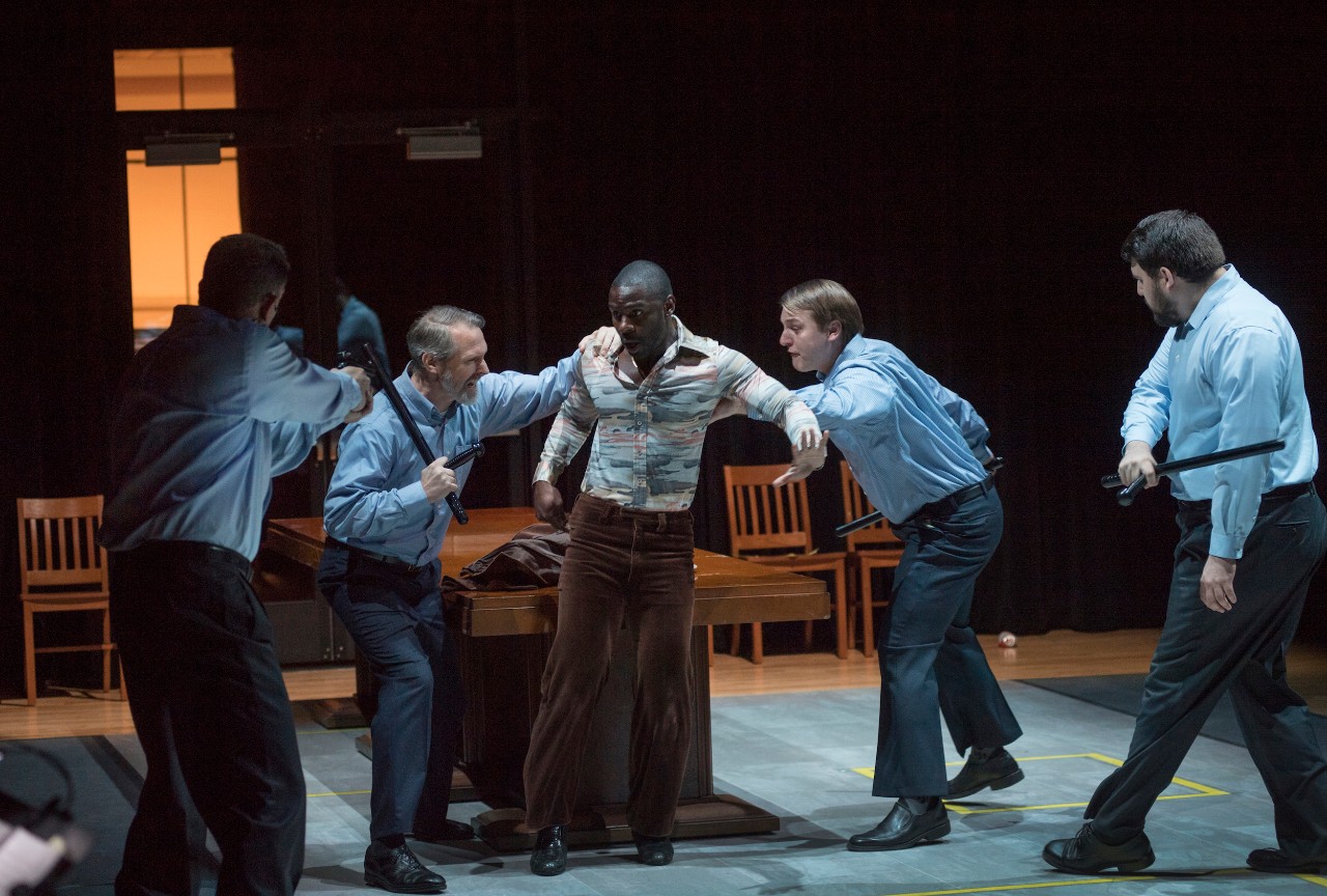 Stage scene shows man being arrested by police