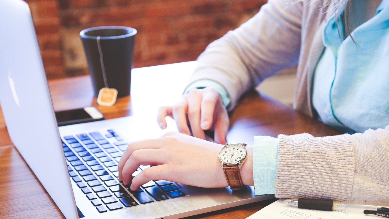 Person writing on a laptop.