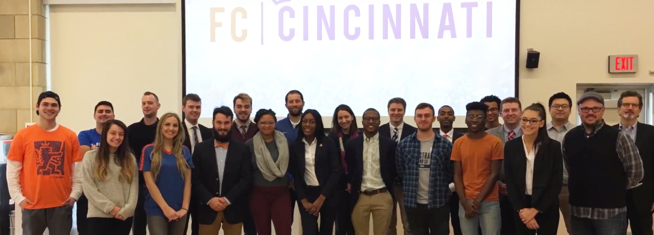 About two dozens students and faculty members standing in a row for a group photo