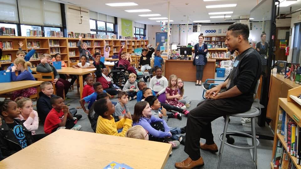 UC CCM Brian Nabors sits before a music class of elementary students.