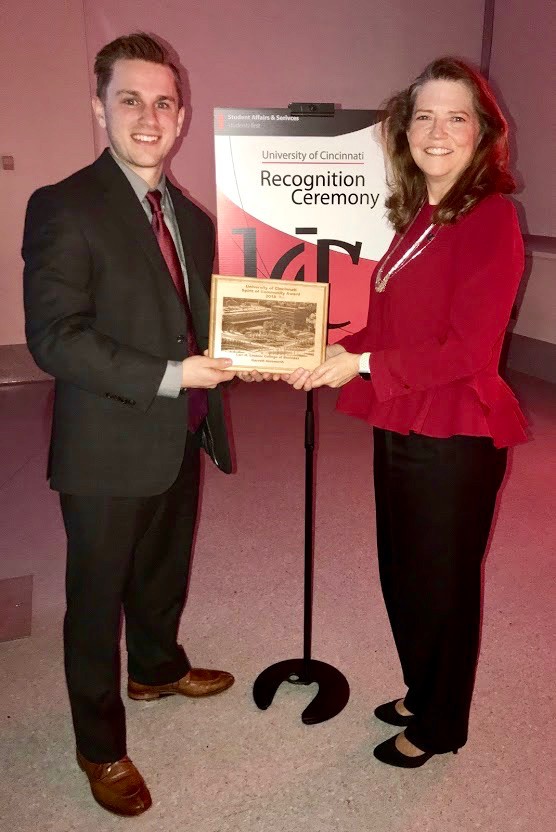 Garrett Ainsworth stands with a UC faculty members as he holds UC LCOB's Spirit of Community award.