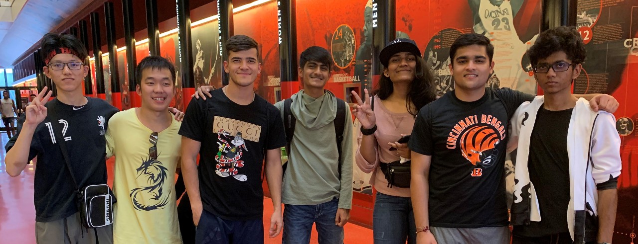 7 international students pose in front of a mural in the Richard E. Lindner Center