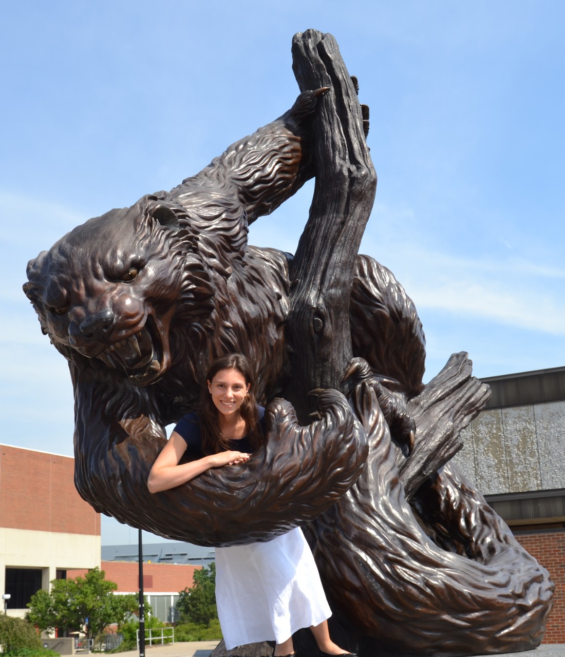 A young woman stands leaning on a statue of the UC Bearcat mascot