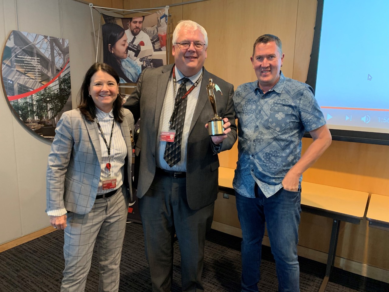 From left, UC Police Chief Maris Herold, UC Public Safety Director James Whalen and  I & Eye Creative Director Bob Igoe stand with the Telly Award that UC Public Safety received for the 2018 UCPD recruitment video that I & Eye filmed.