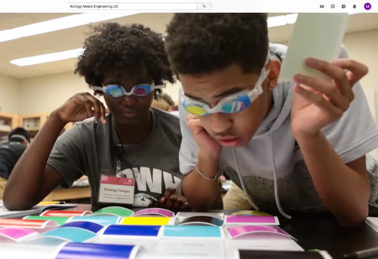 Two students wearing goggles peer at flashcards.