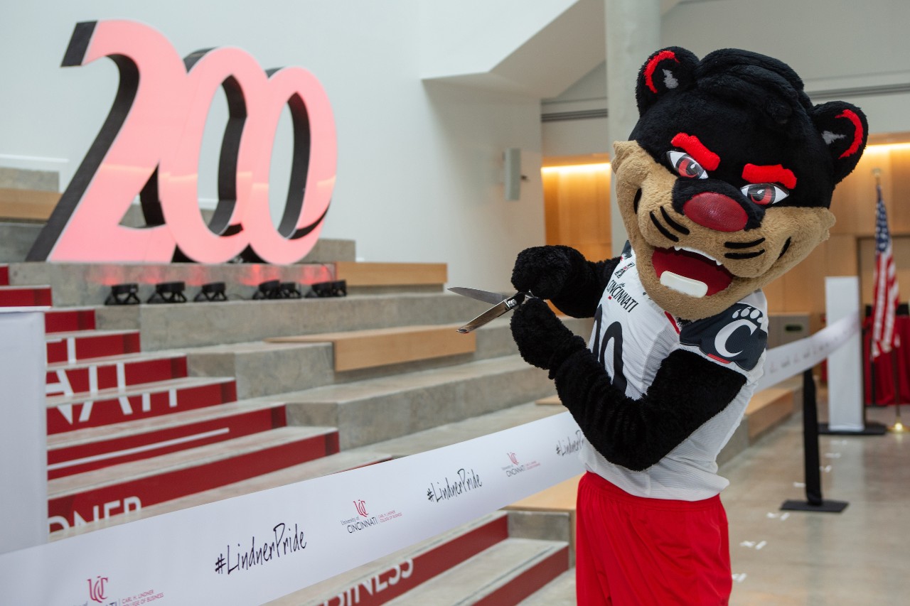 The Bearcat holds a pair of scissors while posing with the ceremonial ribbon. 