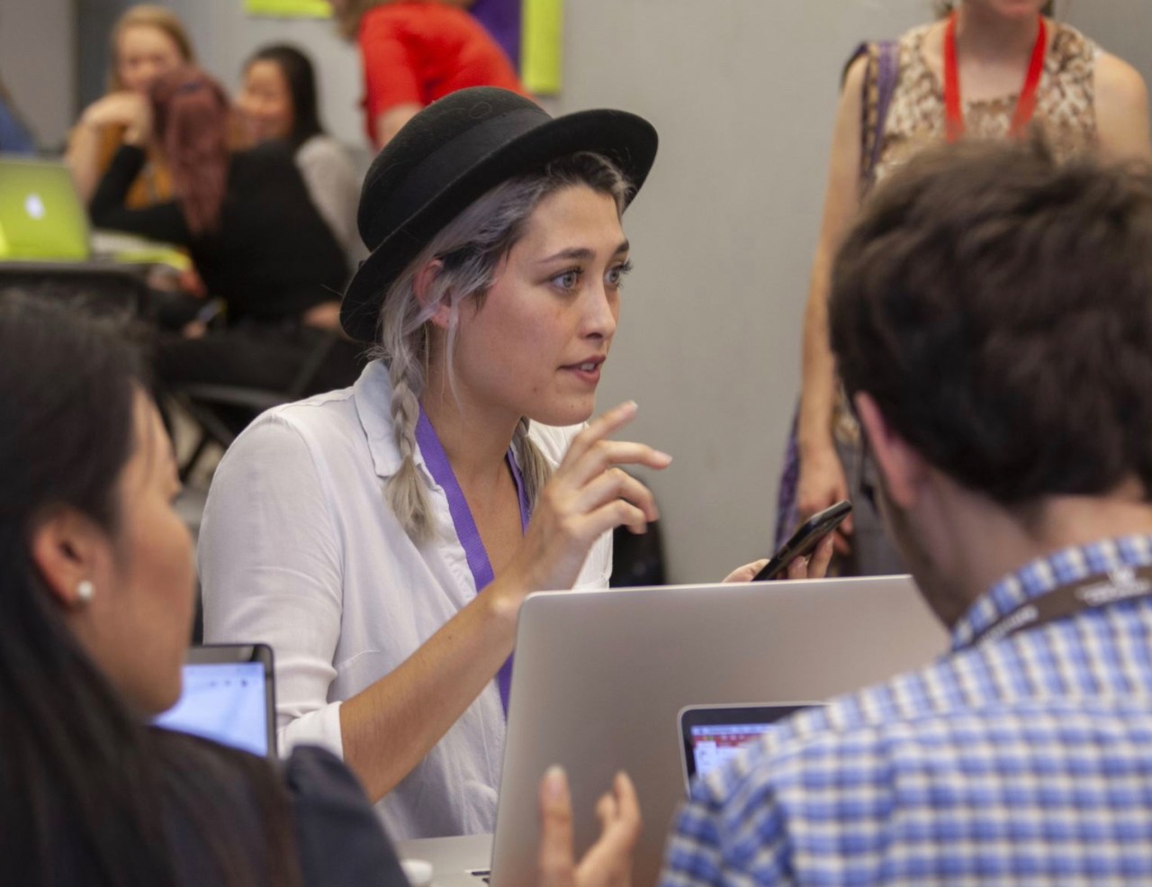 A woman sits at a table of students in a discussion.