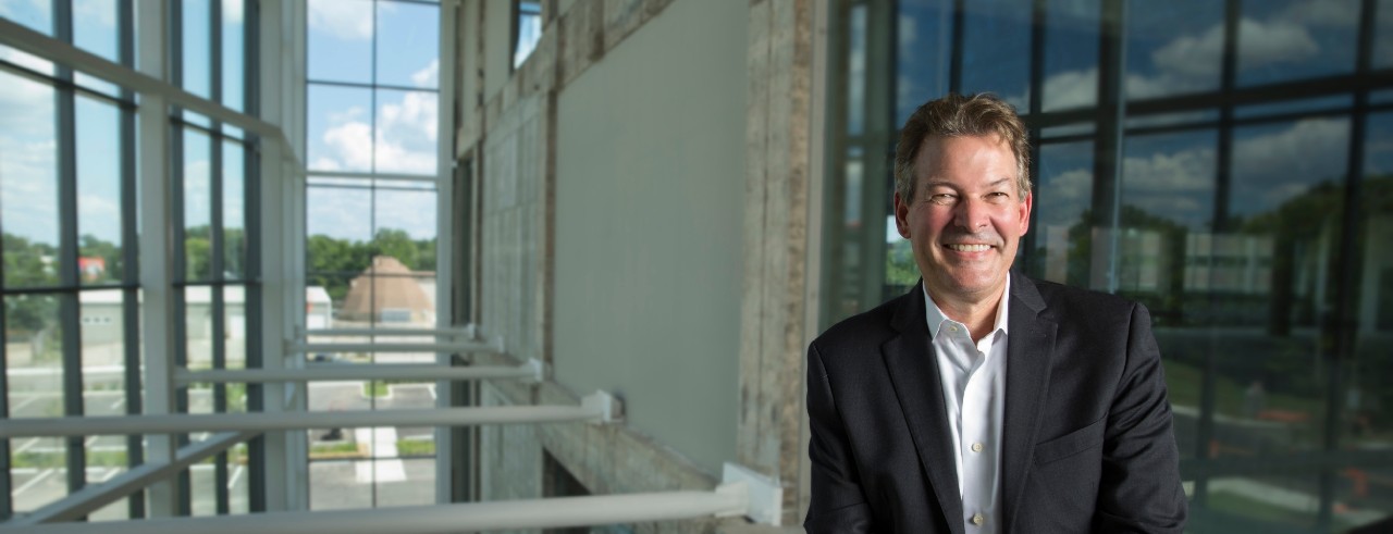 David Adams smiles inside glass lobby