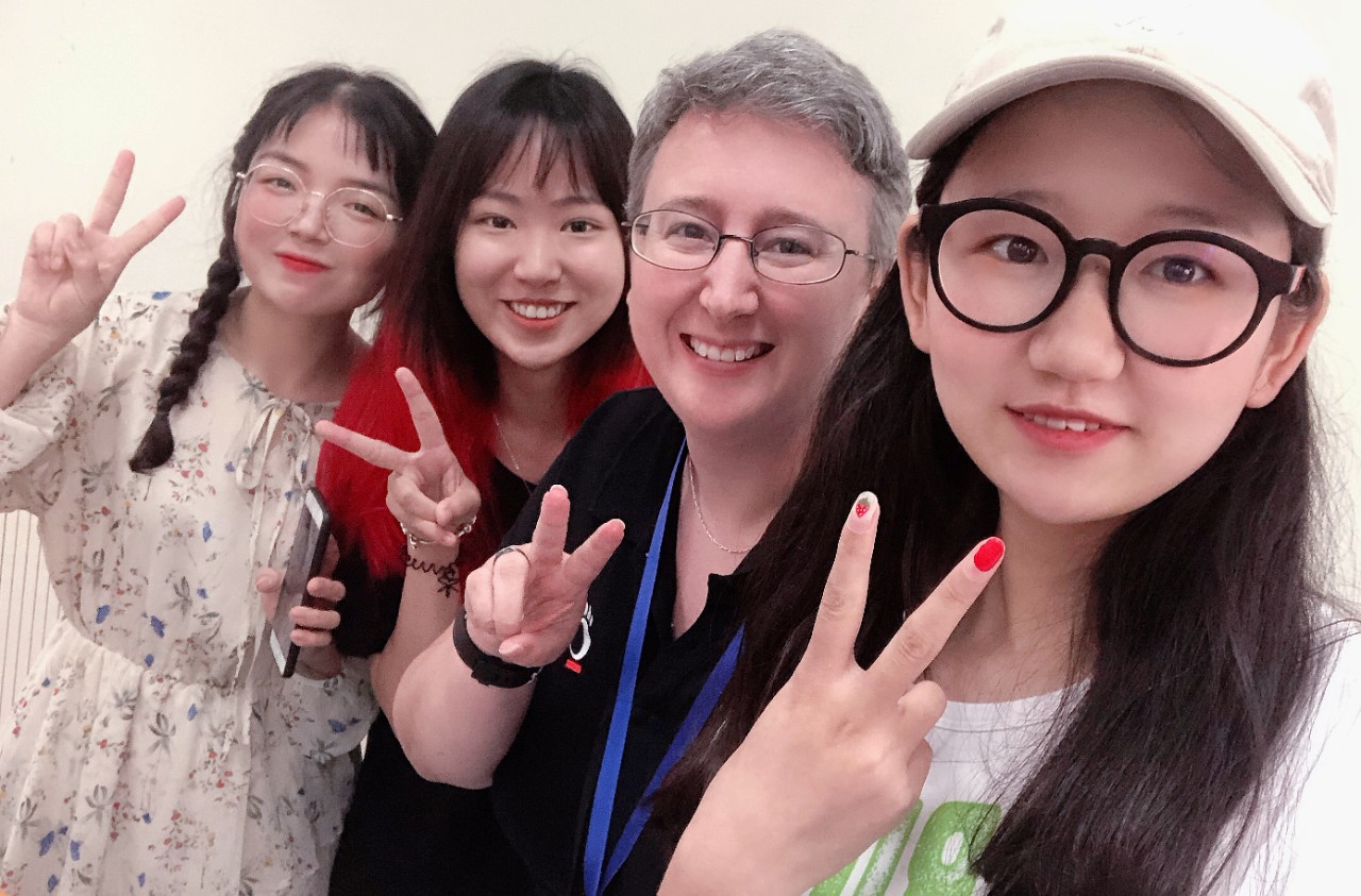 Students flash peace and love signs posing with their professor.