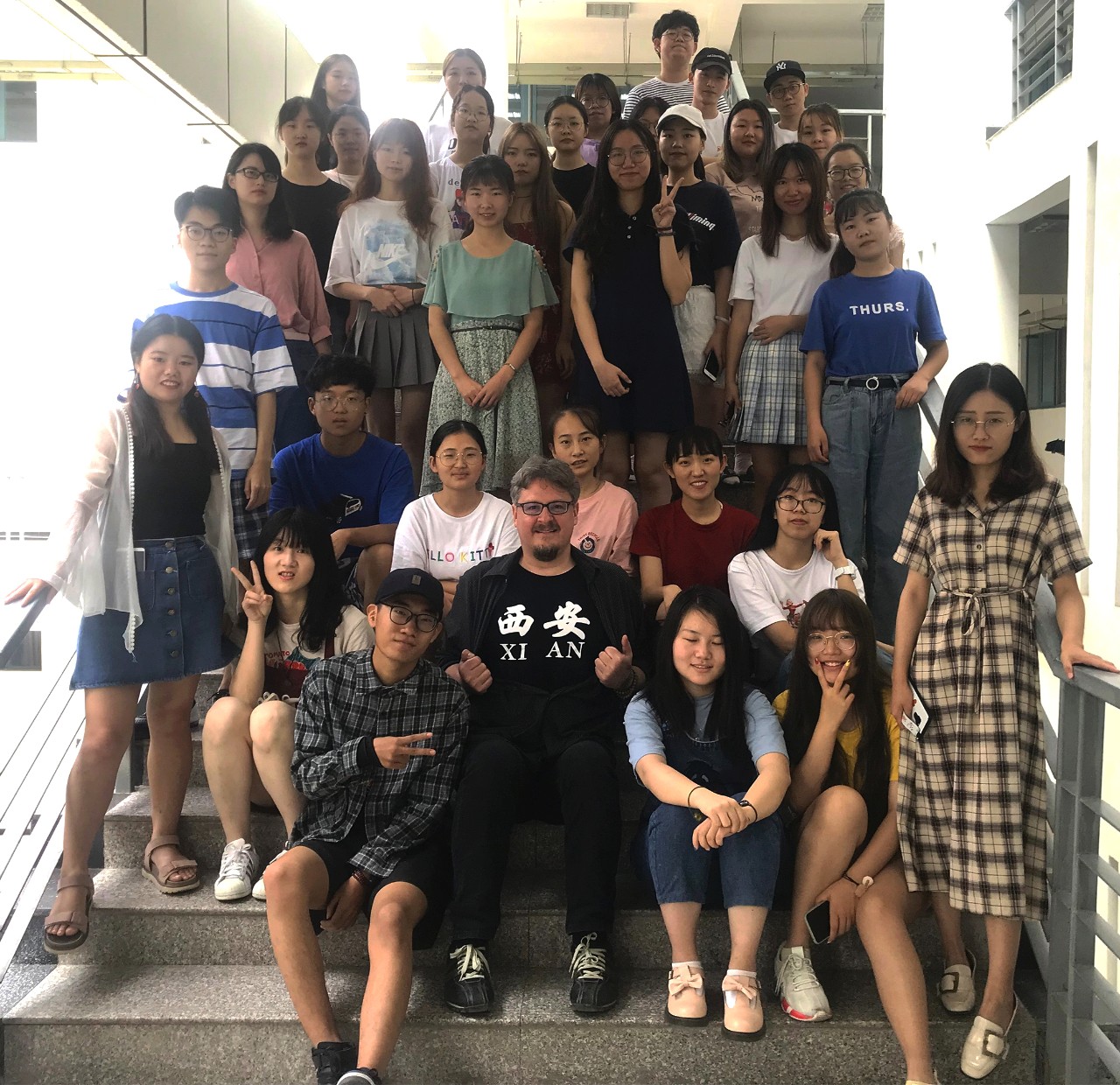 A group of students poses with their teacher on a staircase