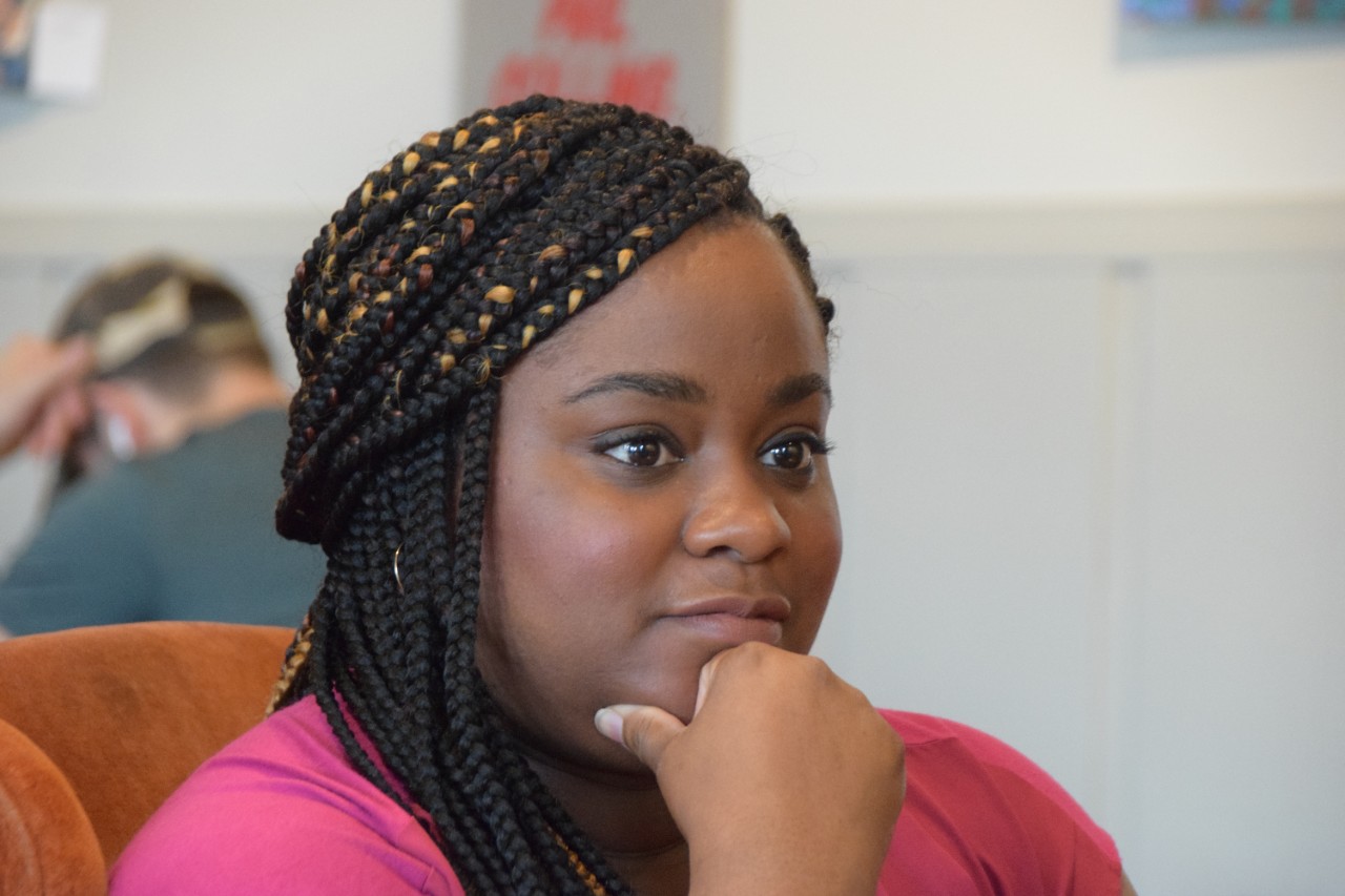 Rashida Manuel sits, looking pensive, with her chin resting on her hand. 
