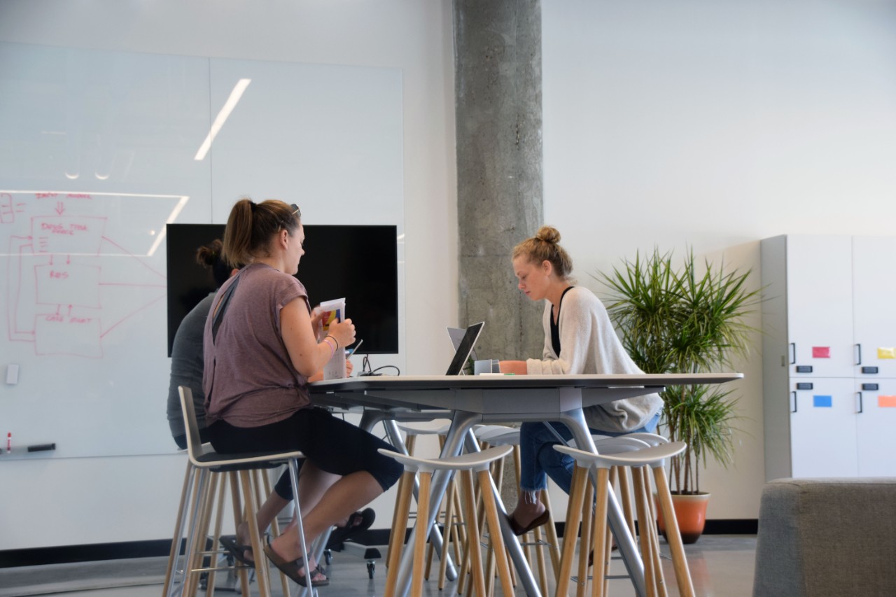 Students gather at a table to collaborate in an open, modern space.