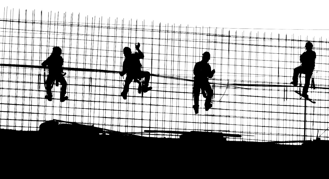 The silhouettes of construction workers on a job site.