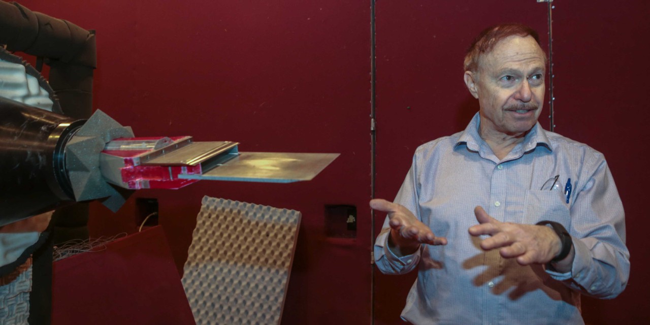 Ephraim Gutmark stands in front of a jet engine in a soundproof UC lab.